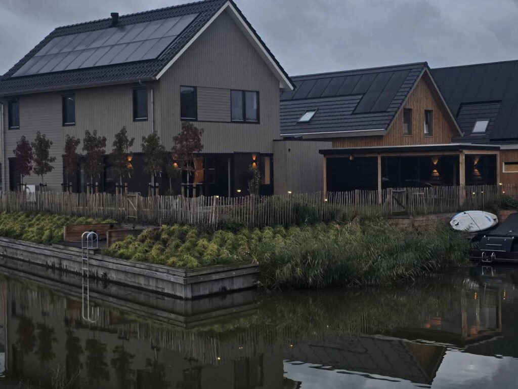 Tuin aan het water met houten walbeschoeiing en leibomen in Leeuwarden